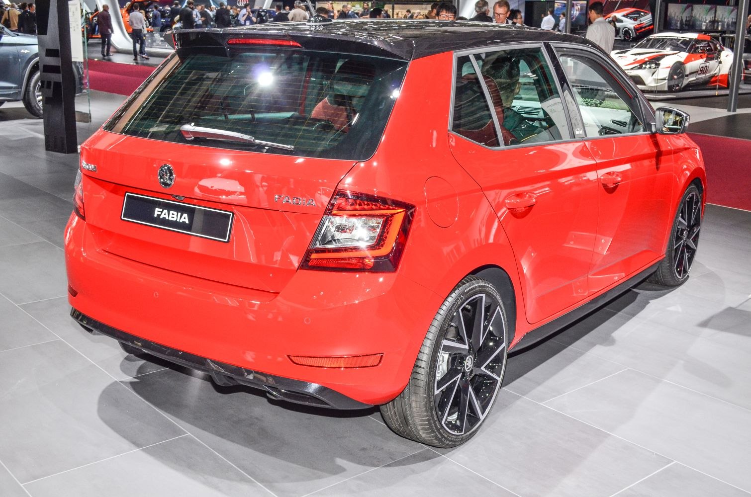 Red hatchback with black roof and sporty black wheels rear view