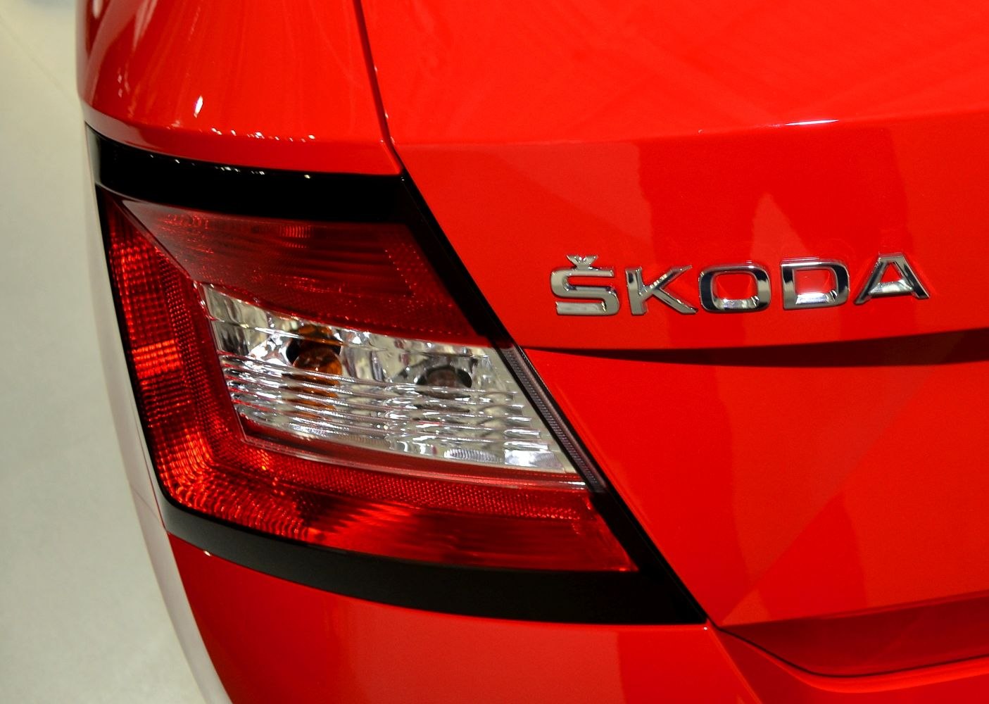 Rear tail light and Škoda brand logo on red car surface