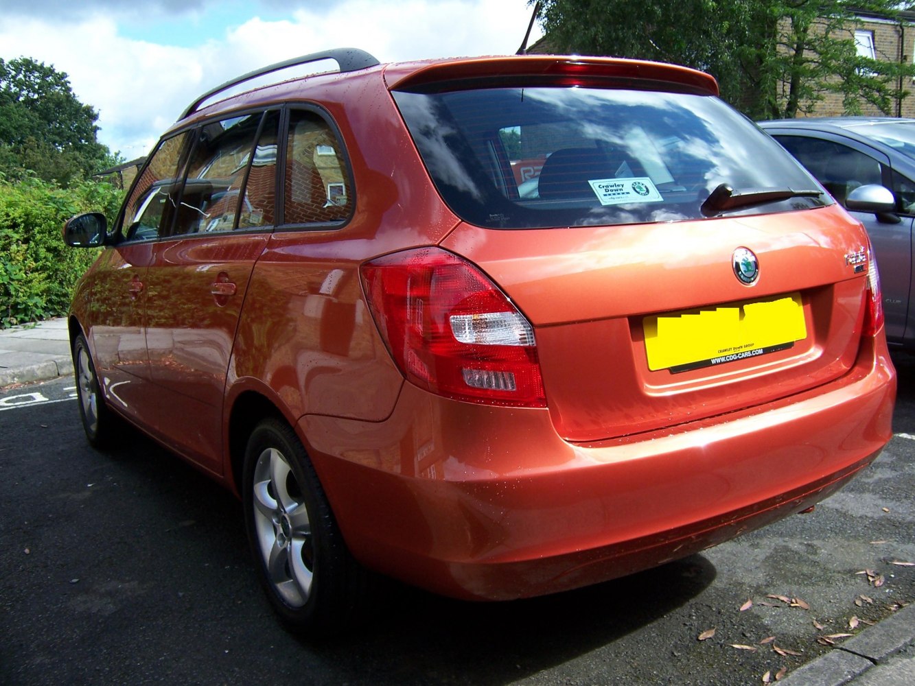 Rear-side view of orange estate car with roof rails and alloy wheels