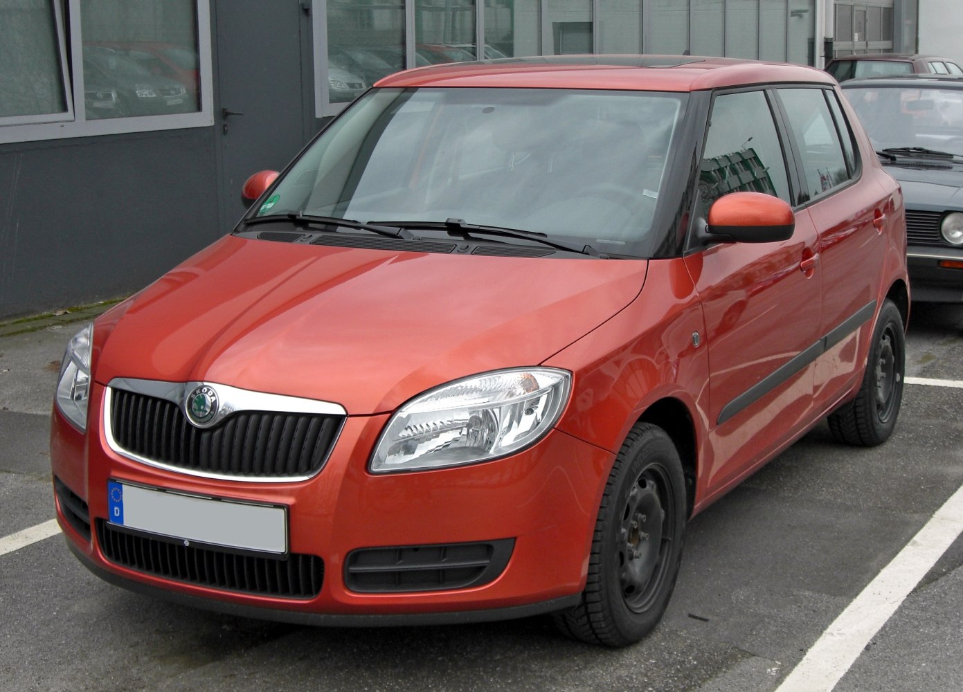 Red hatchback with black grille and integrated headlights