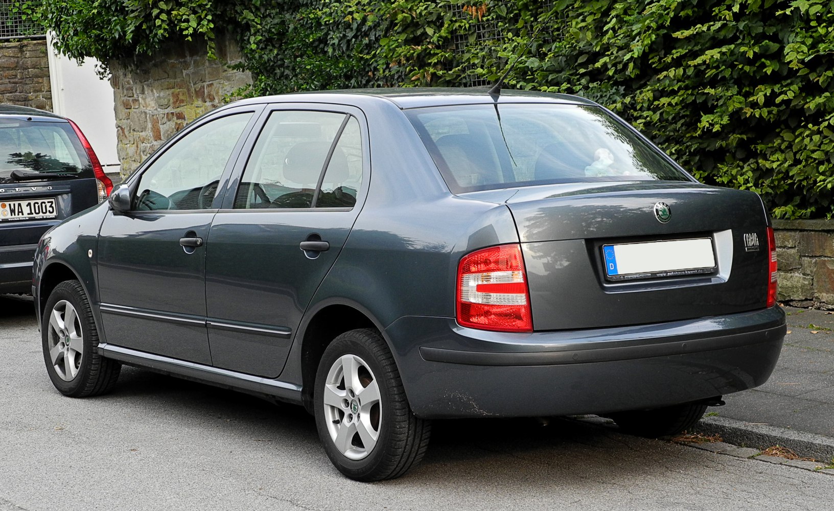 Rear and side view of grey compact sedan with distinctive taillights