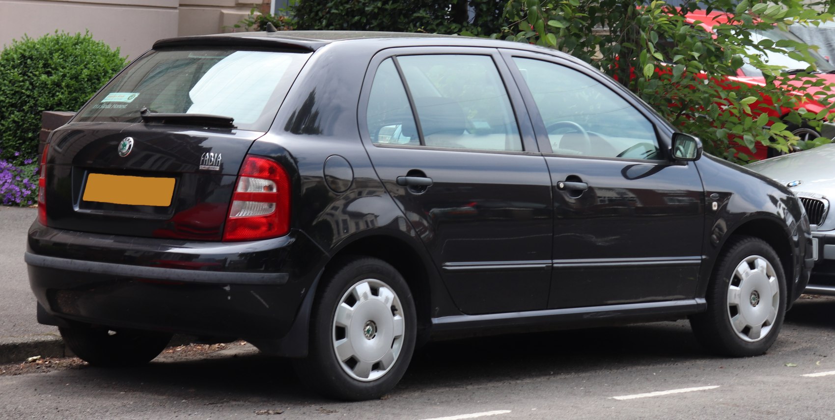 Rear and side view of a black five-door hatchback with classic taillights and wheel covers.