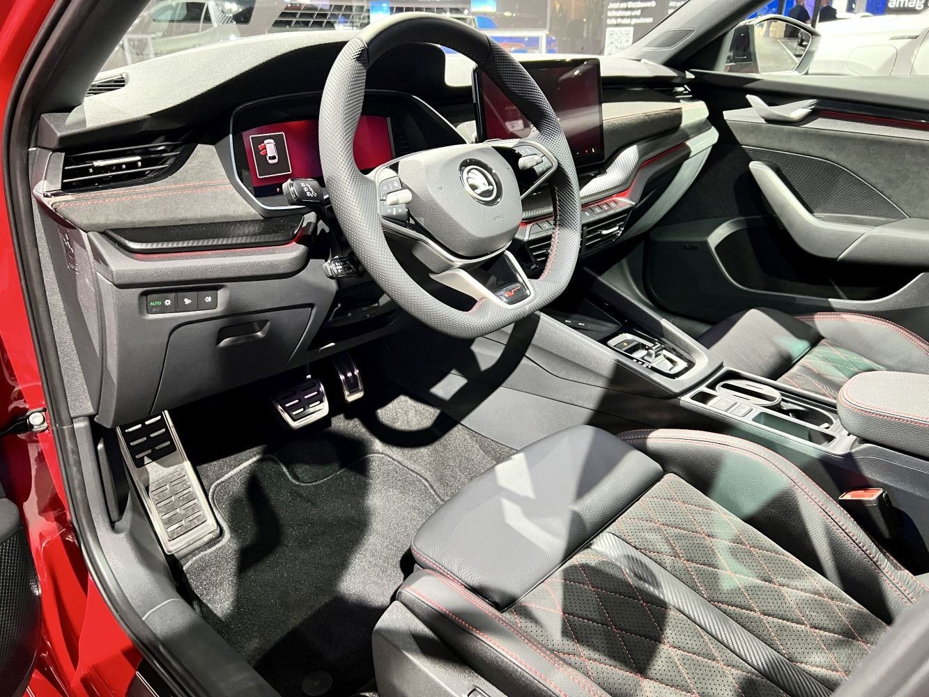 Sporty steering wheel with digital cluster and premium upholstery with red stitching.