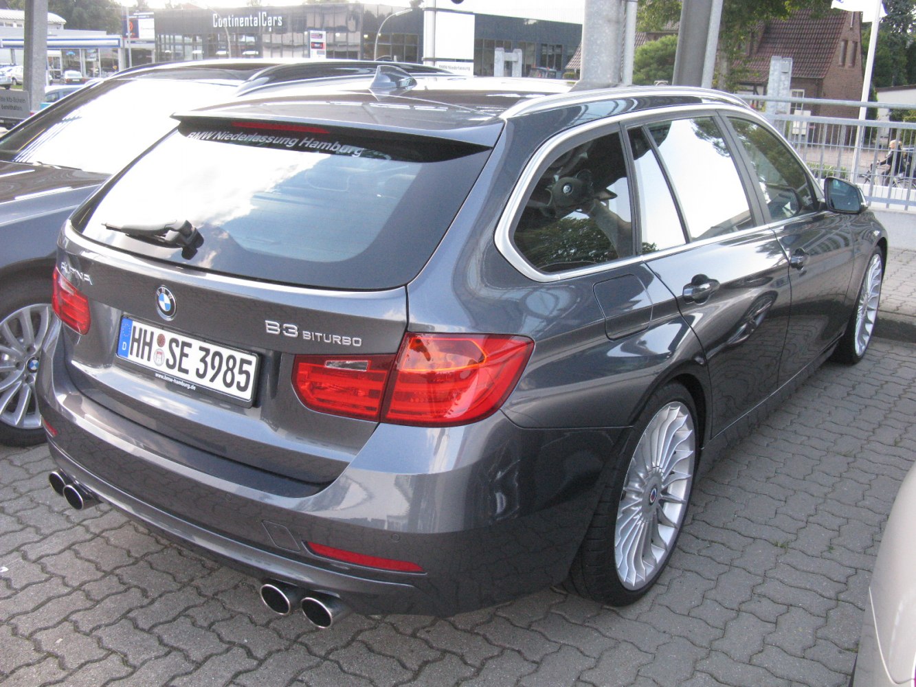 Rear and side profile of a biturbo station wagon with quad exhaust and multi-spoke wheels