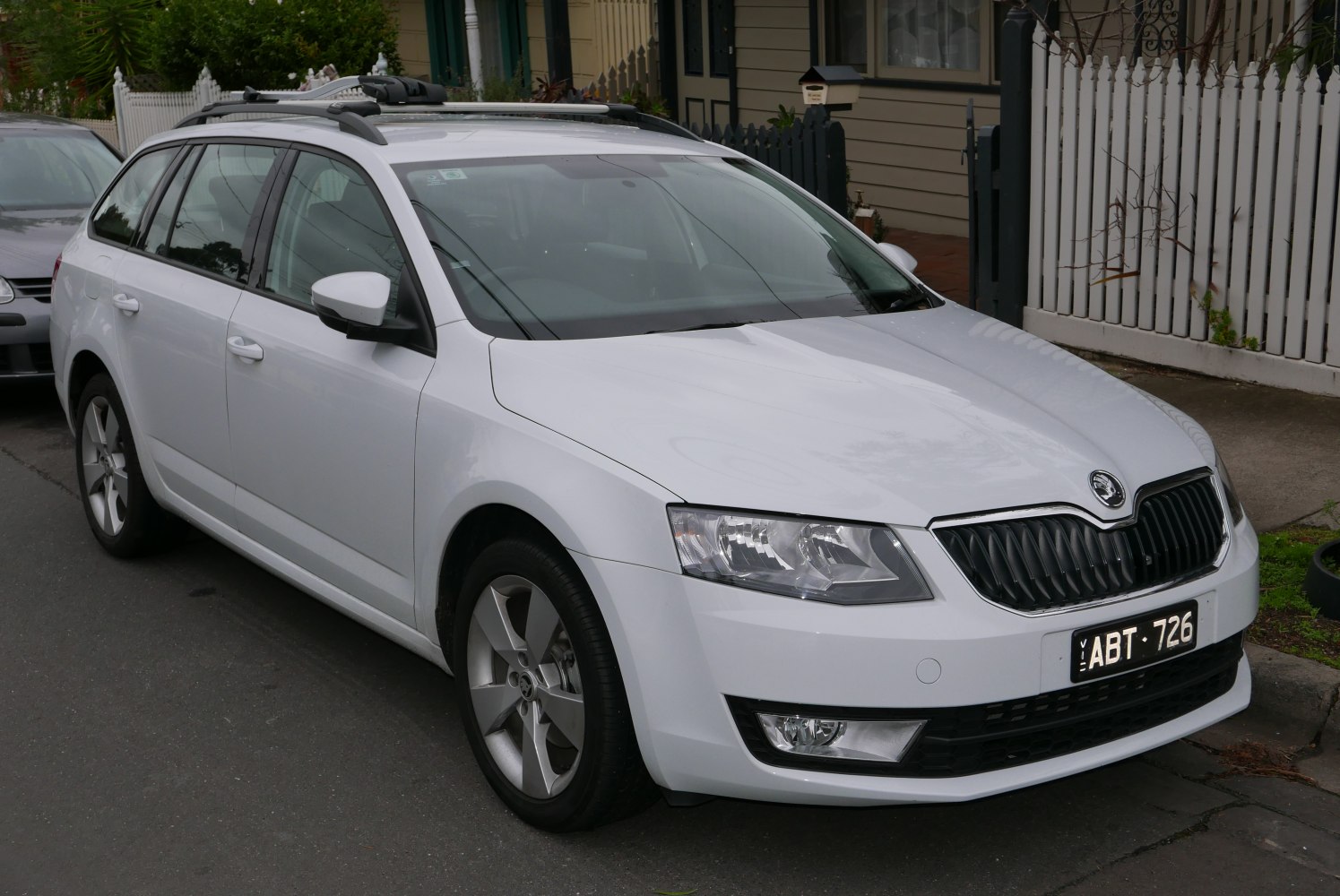 Front side view of white station wagon with roof rails and alloy wheels