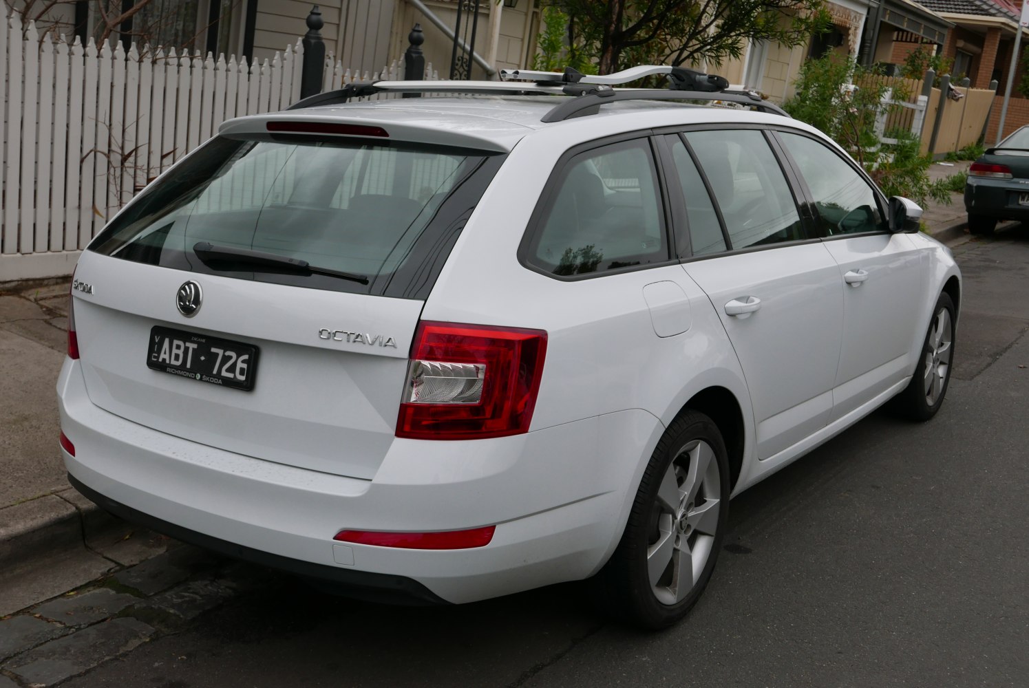 Rear and side view with taillights and roof rack of a white station wagon