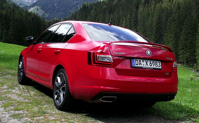 Rear view of a red compact sedan with distinctive tail lights and dual exhaust.
