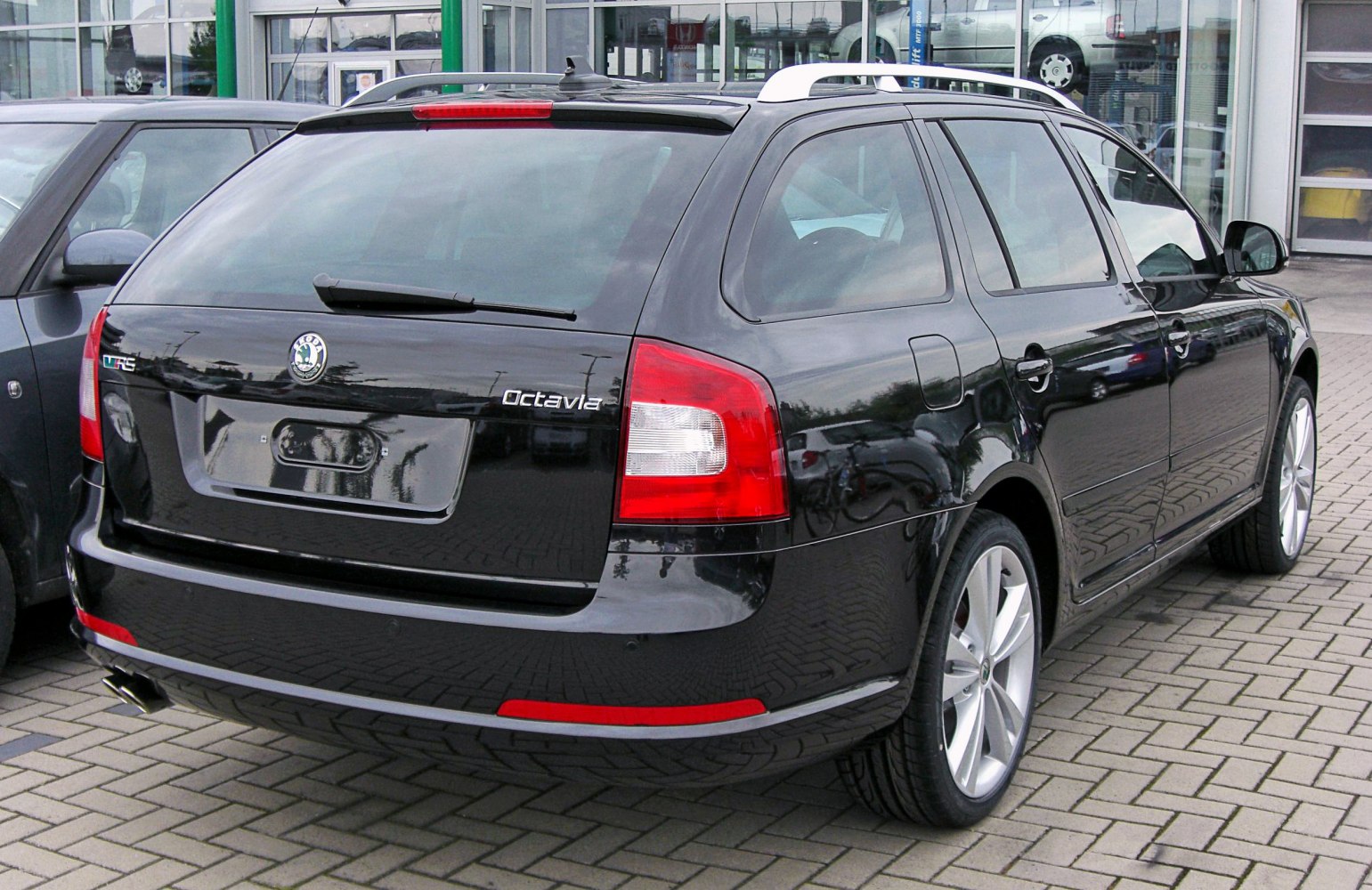 Rear view of a black estate car with distinctive tail lights and roof rails.