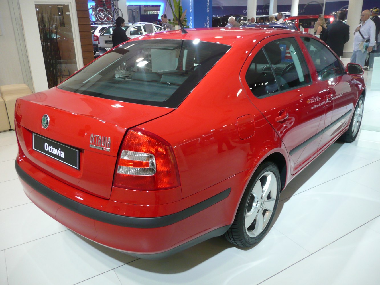 Red sedan rear view with distinctive taillights and black bumper.