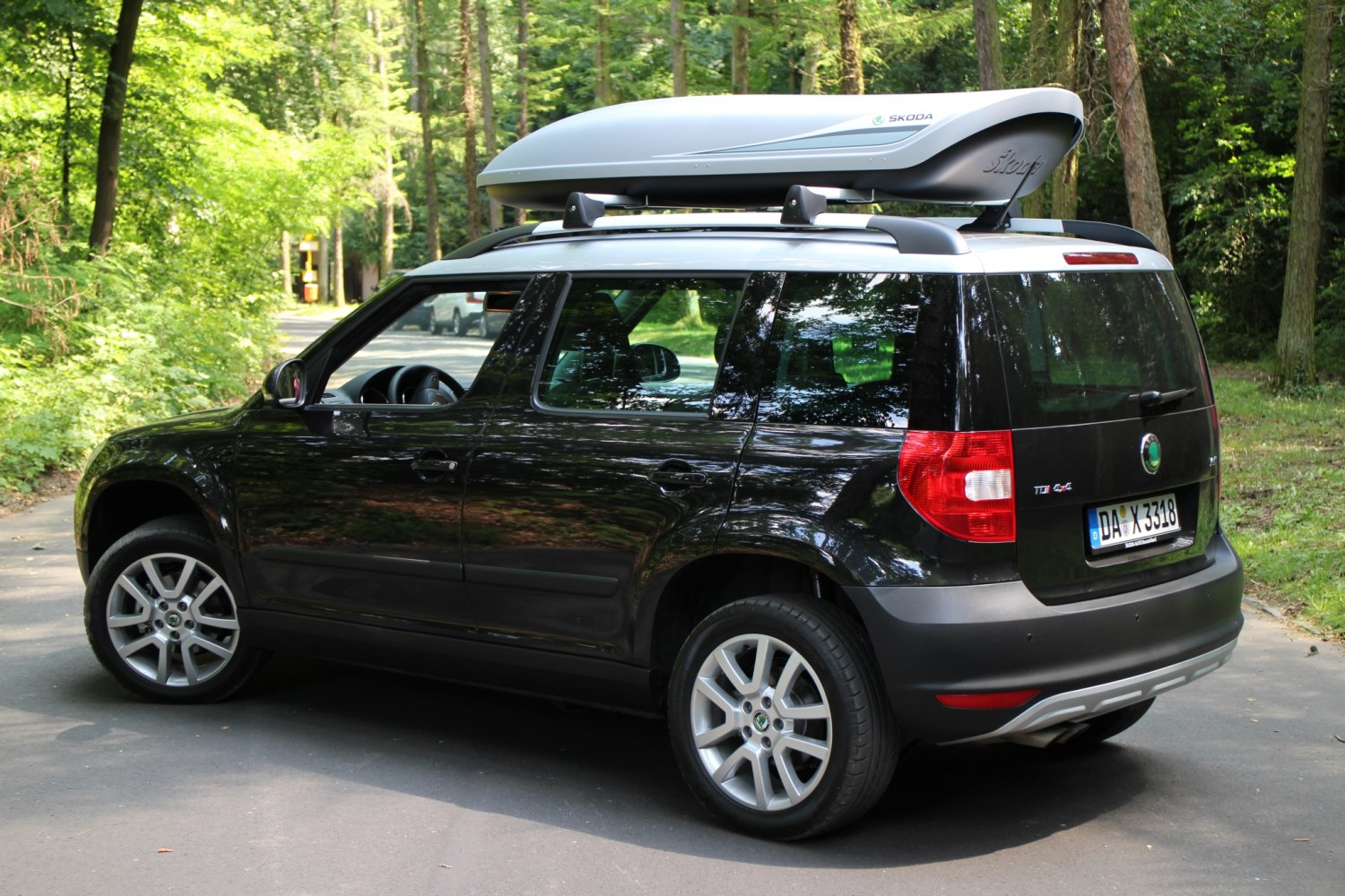 Side view of compact SUV with roof box mounted on roof racks