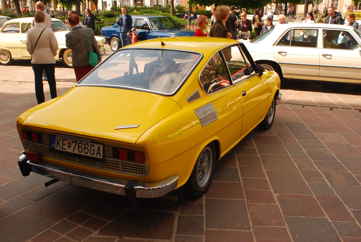 Rear view of a yellow classic coupe with chrome bumper and side vents