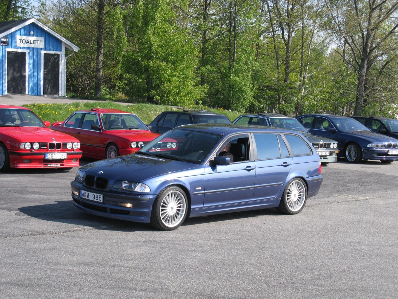 Front side view of touring car with distinctive multi-spoke wheels.