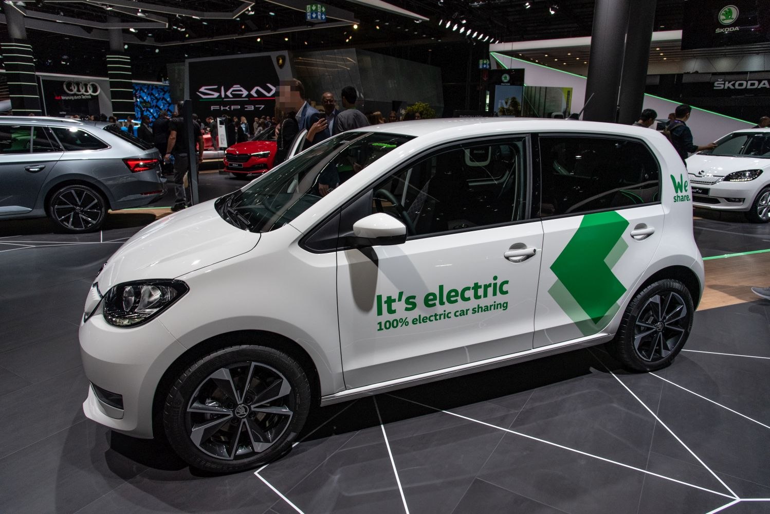 White 5-door electric hatchback with green branding for car sharing