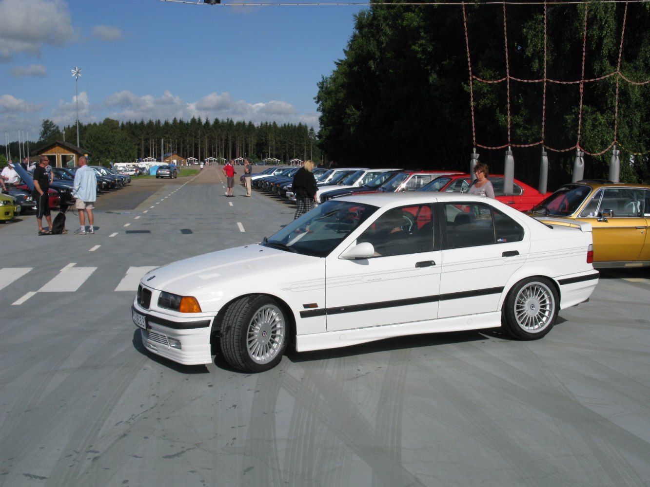White sedan with multi-spoke alloy wheels and rear spoiler