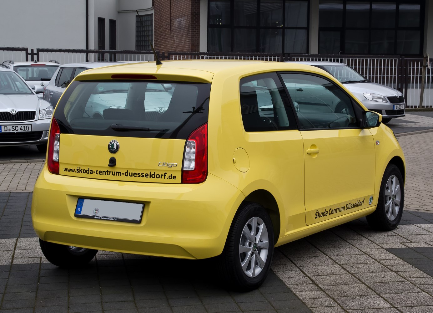 Rear view of yellow 3-door compact hatchback with tail lights and alloy wheels