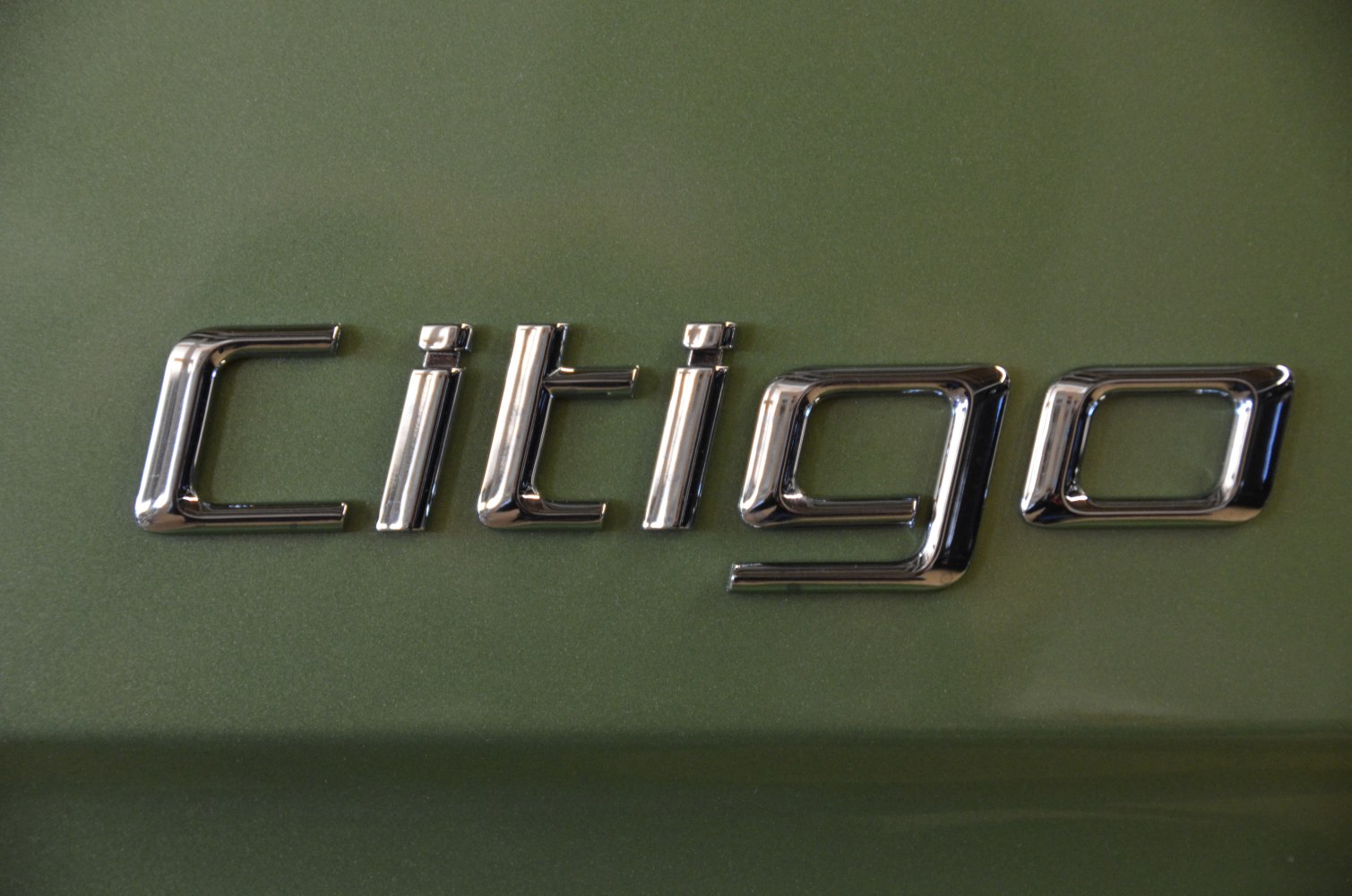 Close-up of a shiny chrome car emblem on a green surface