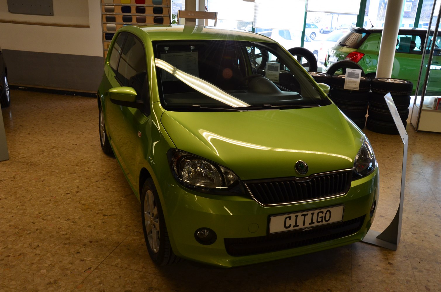Front view of green small hatchback with headlights and grille in showroom