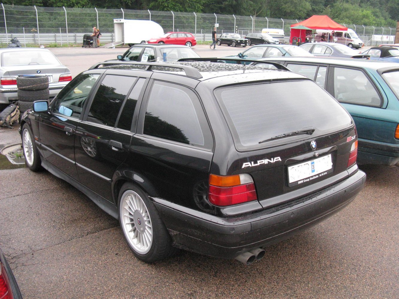 Rear view of black station wagon with mesh wheels and dual exhaust