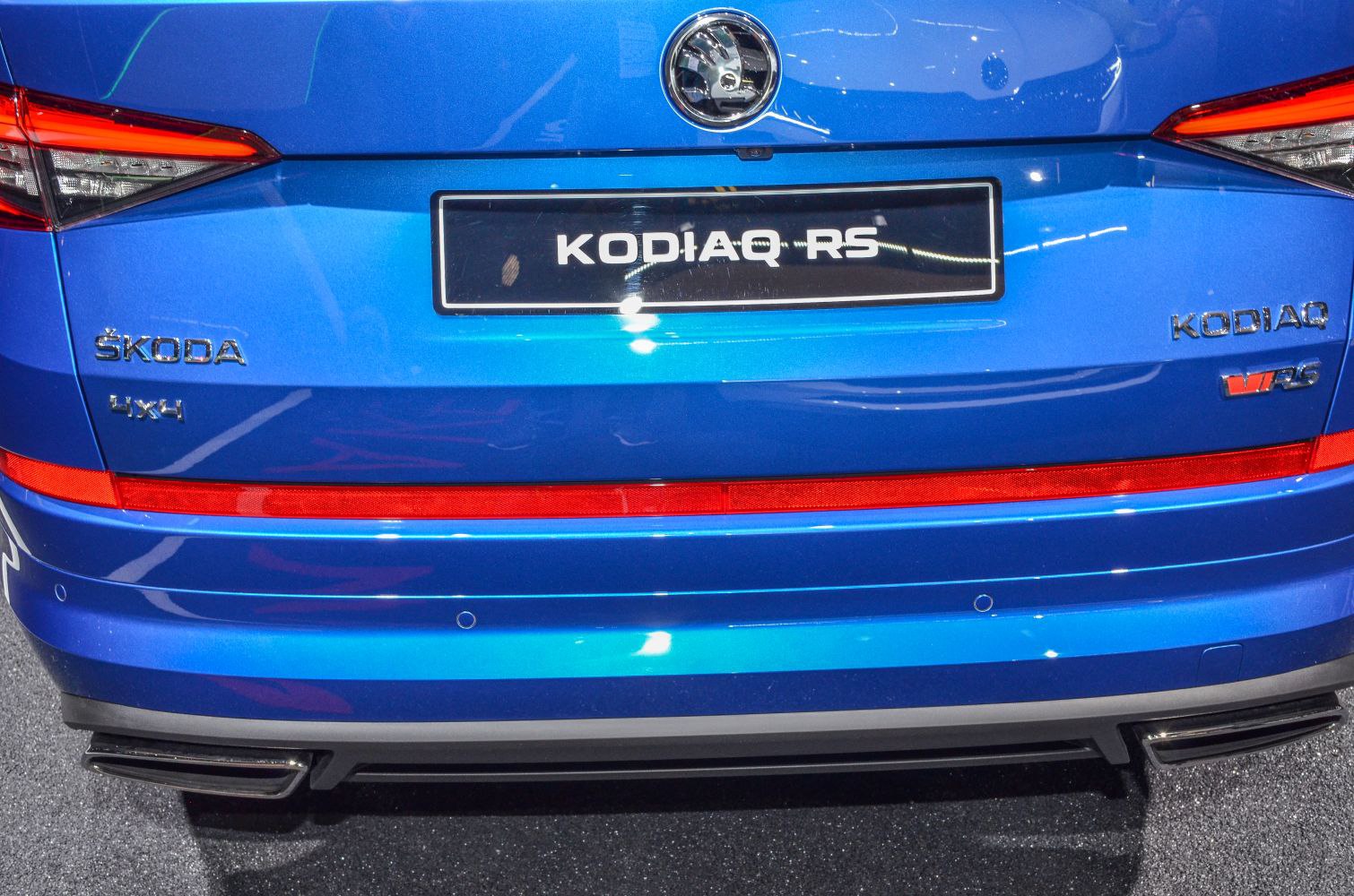 Rear of a blue vehicle with 4x4 badge, tail lights, and exhaust tips.