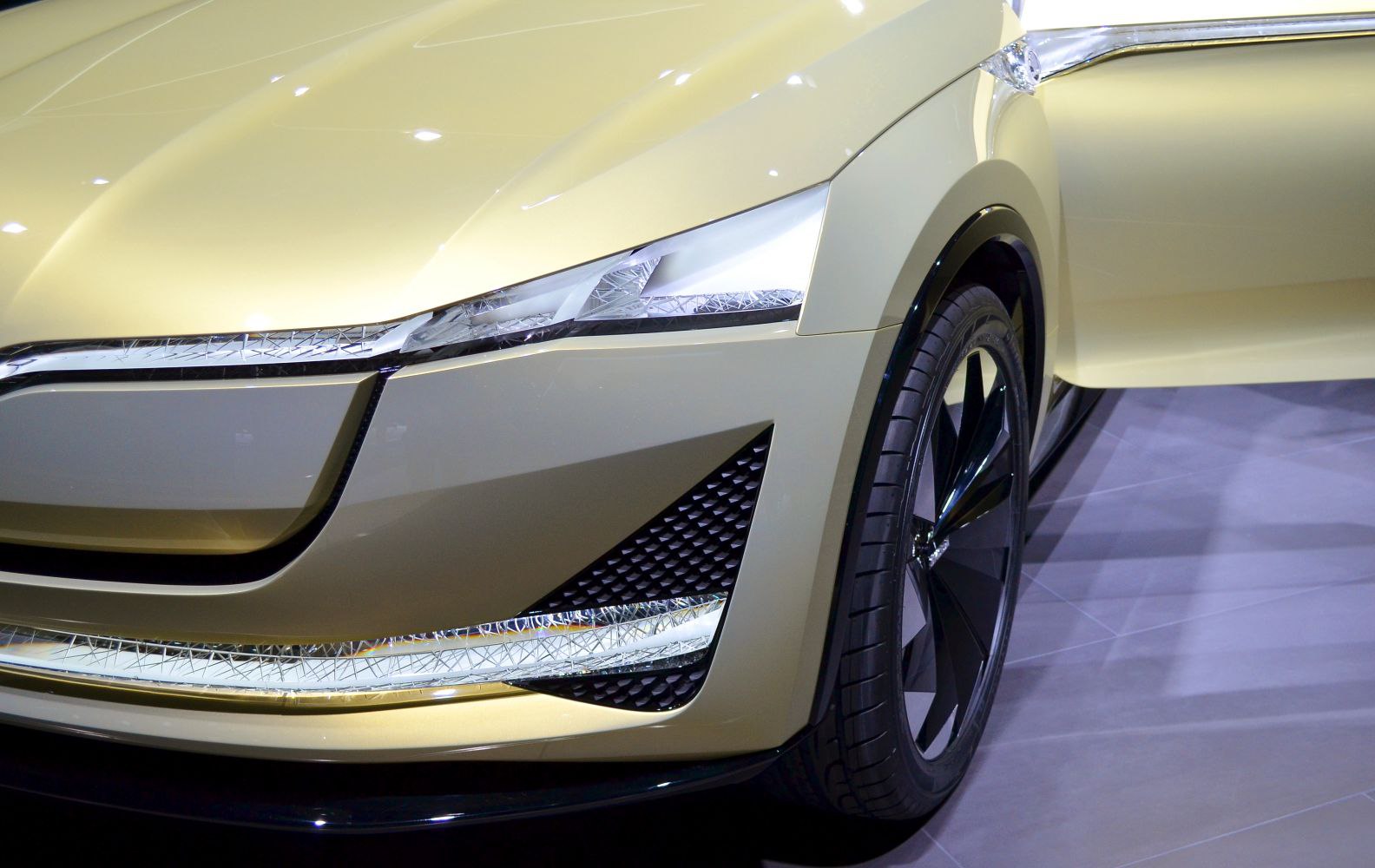 Futuristic concept car front end with sleek LED headlights and distinctive wheel.