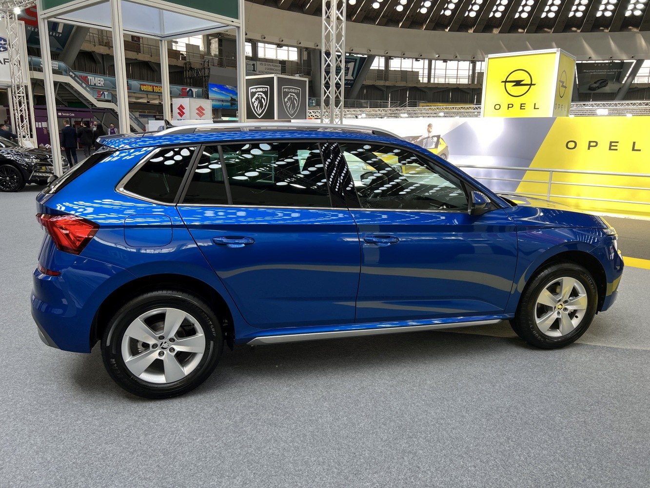 Side profile of a blue compact SUV with alloy wheels at an auto show