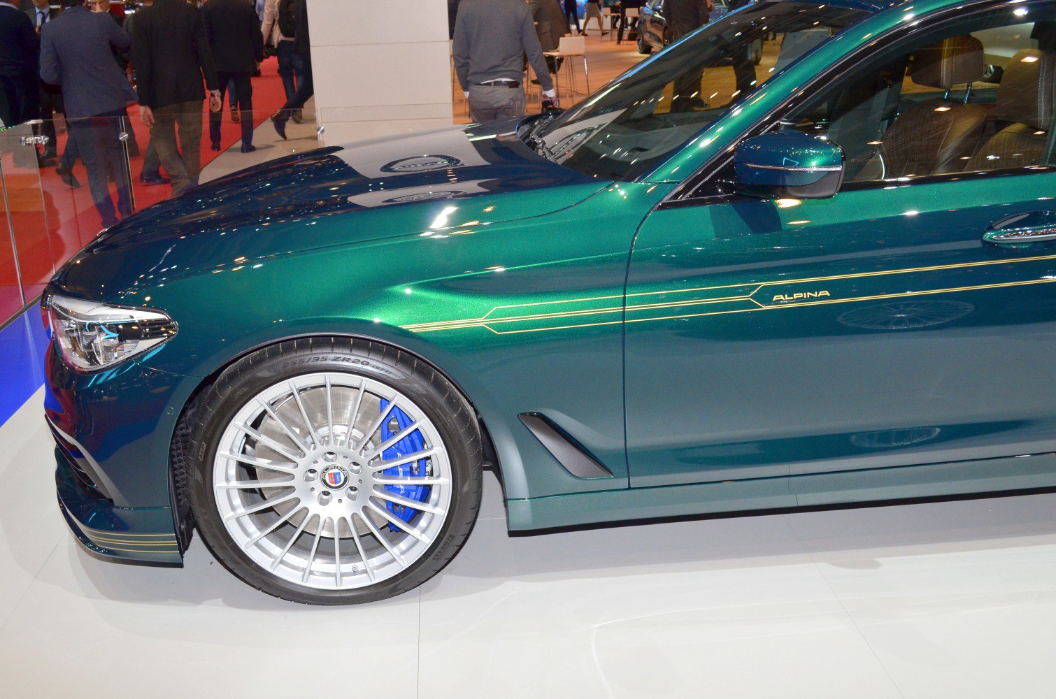 Close-up of front wheel and side body with Alpina striping and blue brake caliper