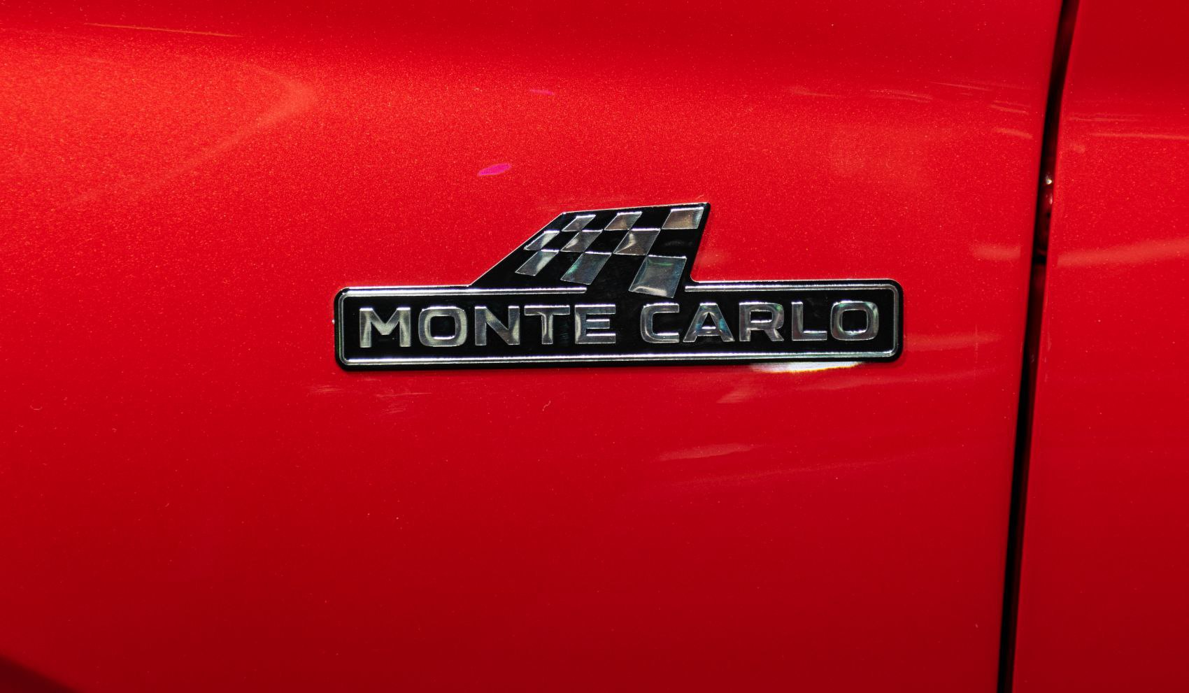 Close-up of Monte Carlo badge with checkered flag emblem on red surface