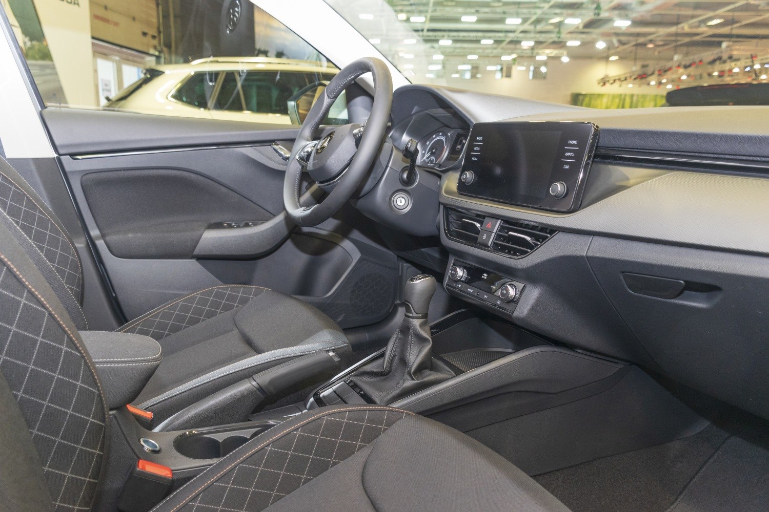 Modern car interior with dashboard, touchscreen, steering wheel, and gear shift