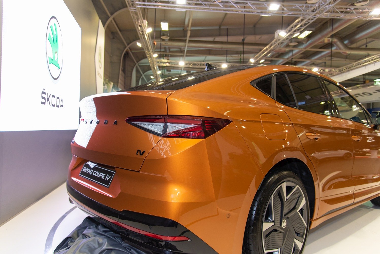 Rear and side profile of orange electric SUV with unique taillights and alloy wheels.
