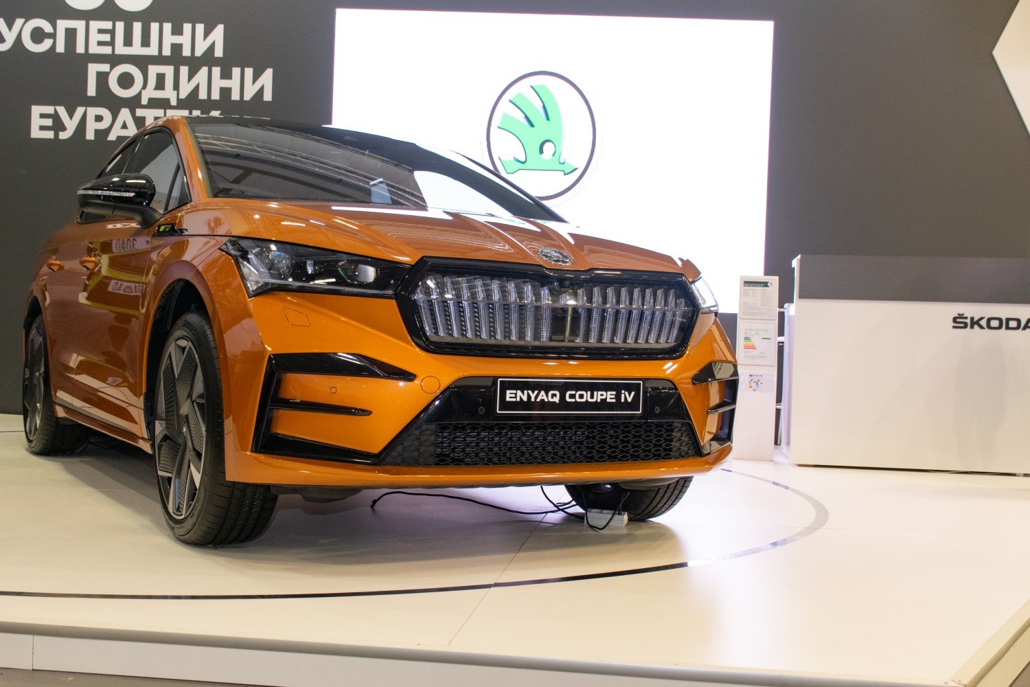Distinctive front grille and sleek headlight design of an orange modern electric SUV.