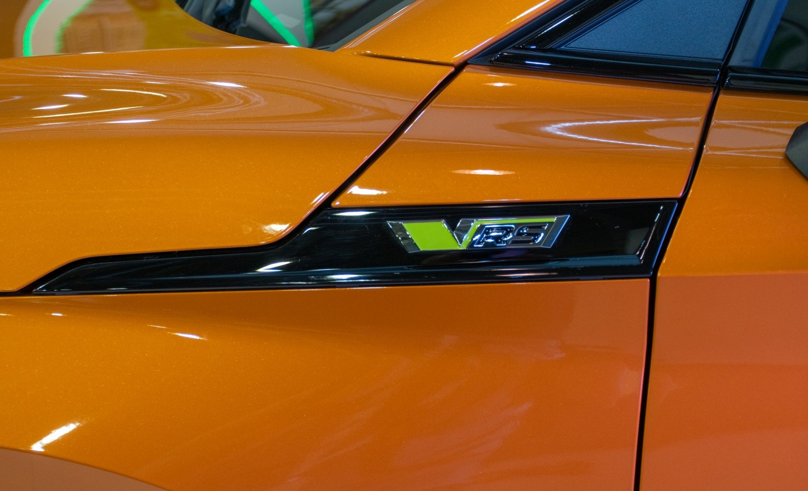 Close-up of VRS side badge on orange vehicle paint.