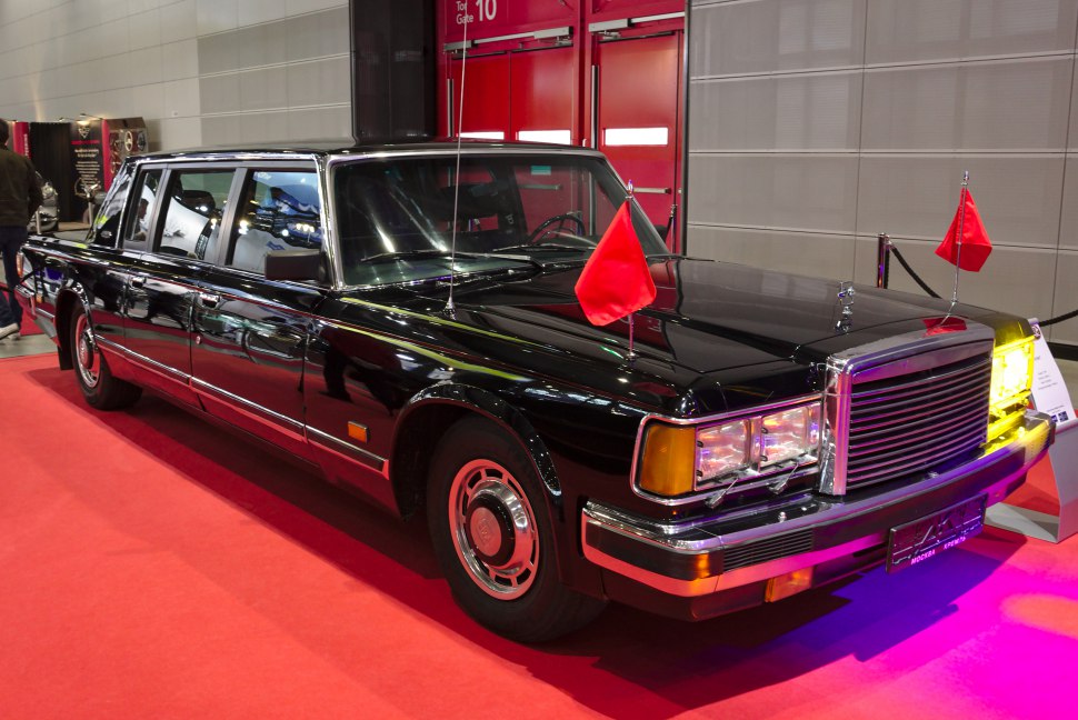 Luxury limousine with dual red flags and chrome grille