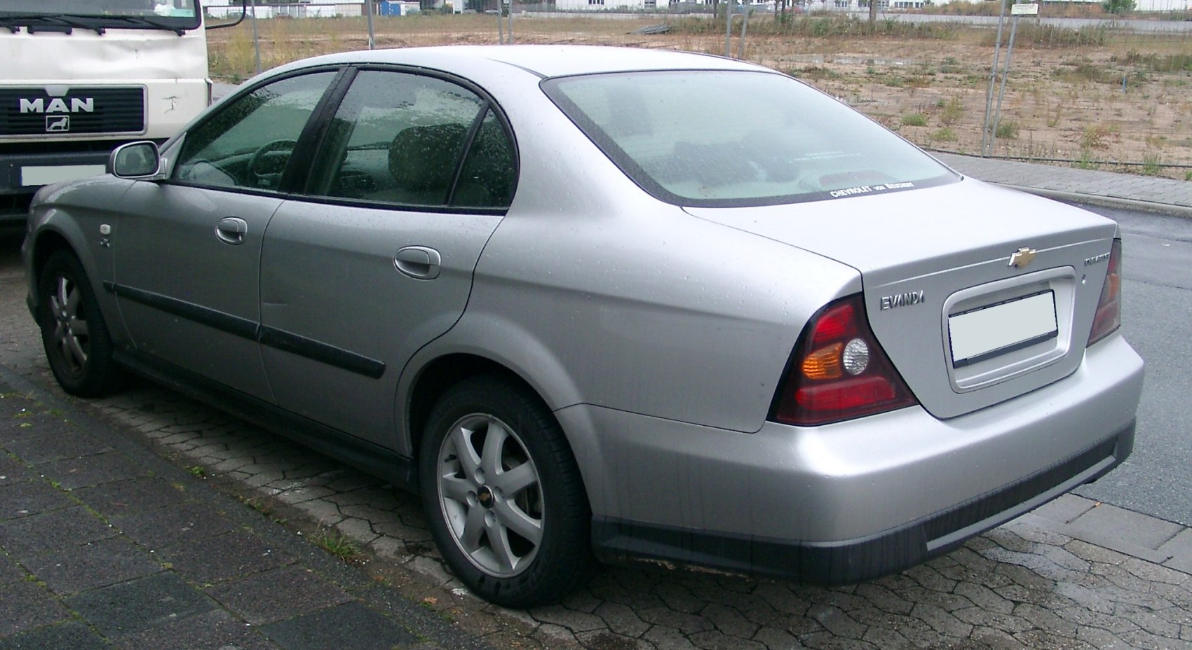 Silver sedan rear side view with distinct tail lights and smooth body lines.
