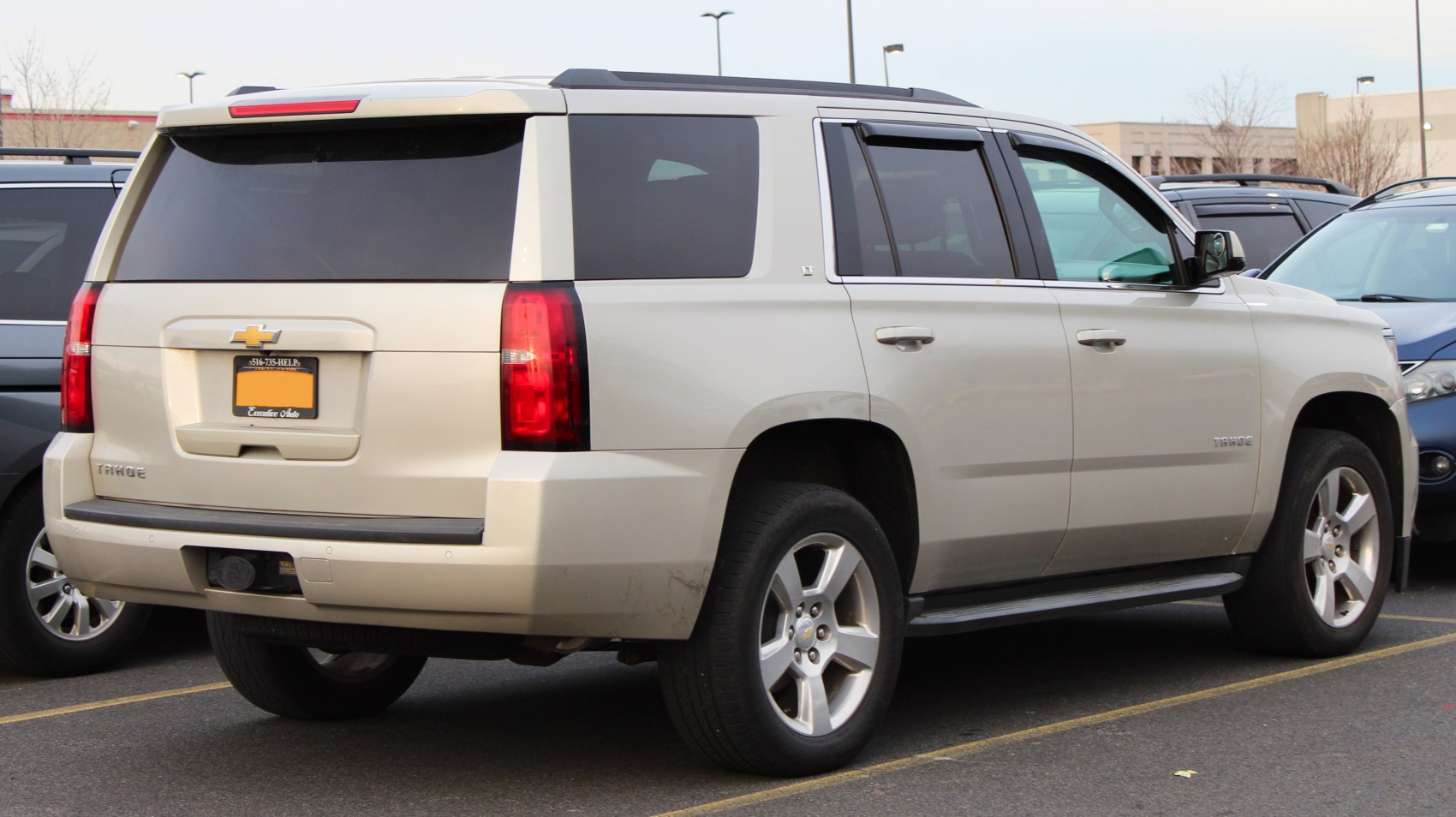 Rear and side view of a large white SUV with tinted windows and red tail lights