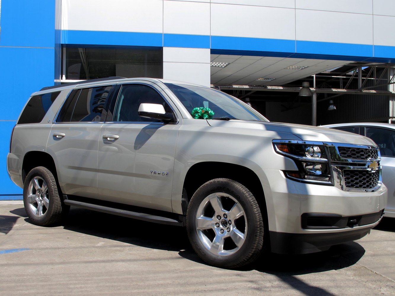 Front and side view of full-size SUV with chrome wheels and bold grille.