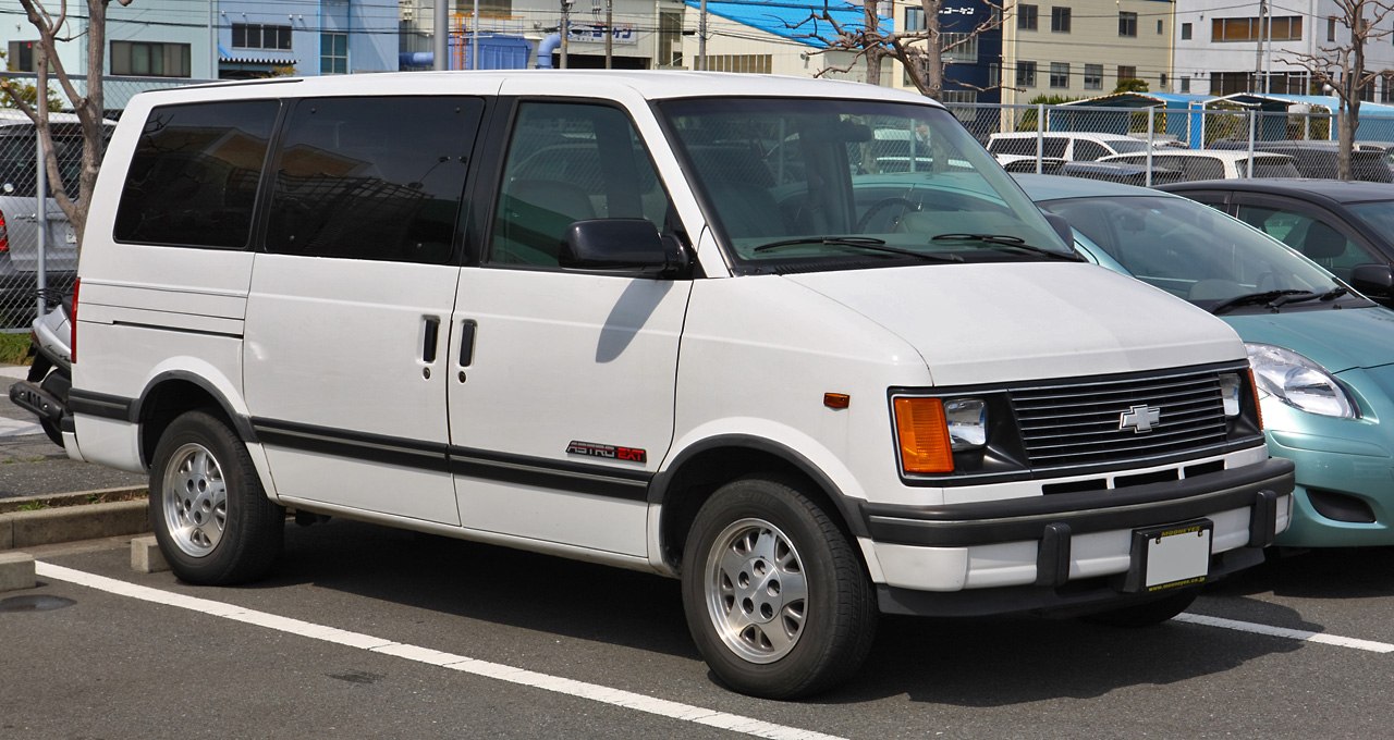 White minivan front side view with dual sliding doors and black trim