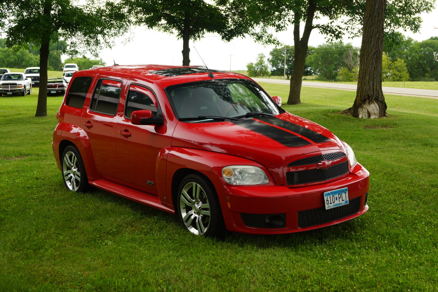 Red vehicle with black hood racing stripe and alloy wheels