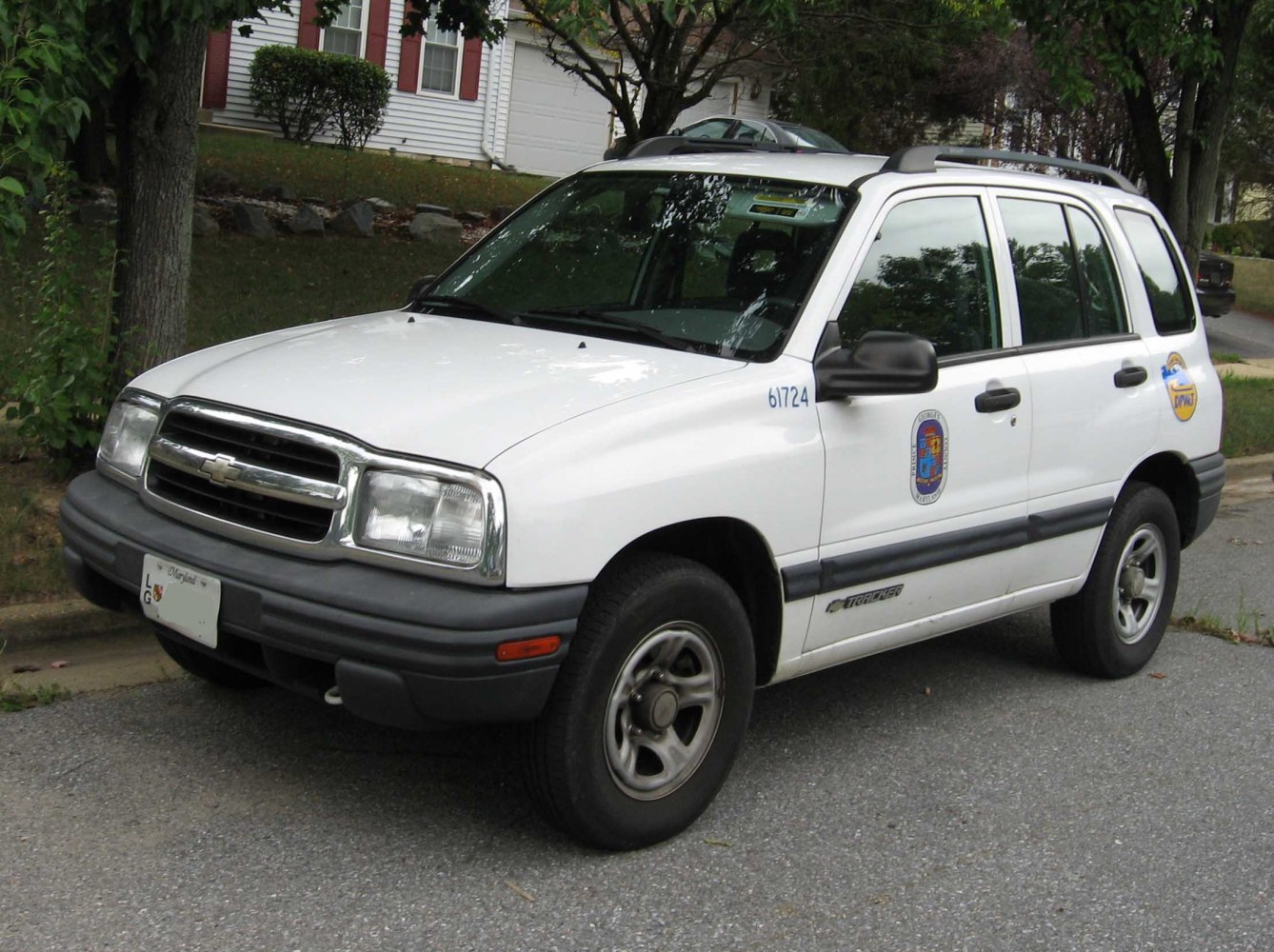 White utilitarian SUV with police decals and roof rack