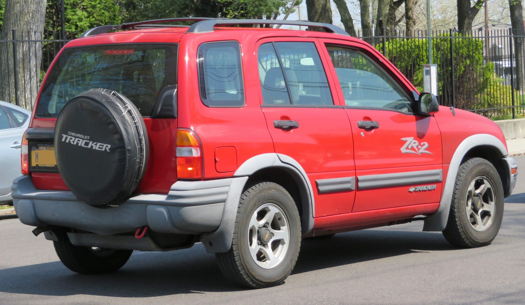 Rear and side view of red SUV with rear spare tire cover and roof rails