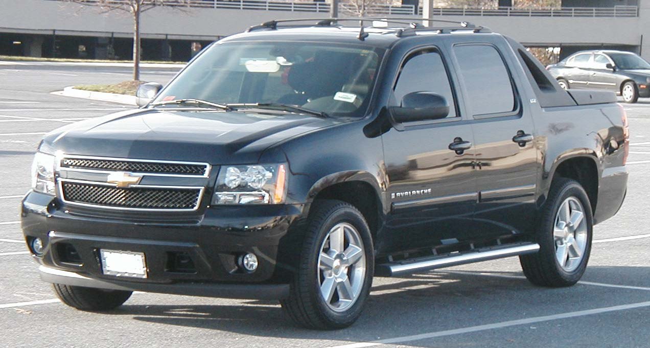 Front view of black crew cab pickup with prominent grille and side steps