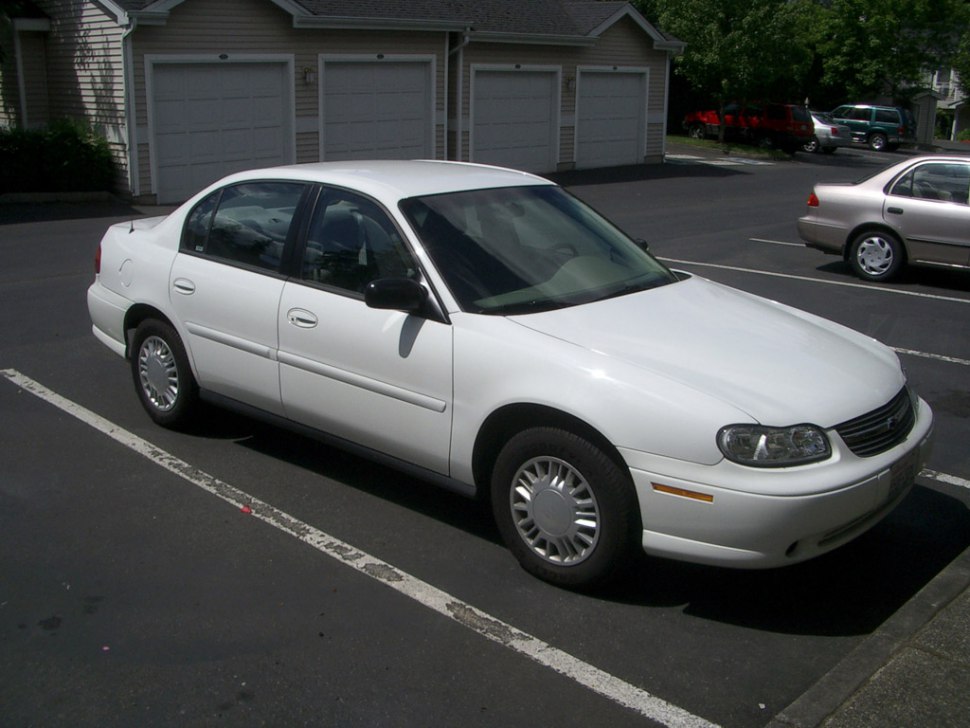 White sedan parked showing front and side view