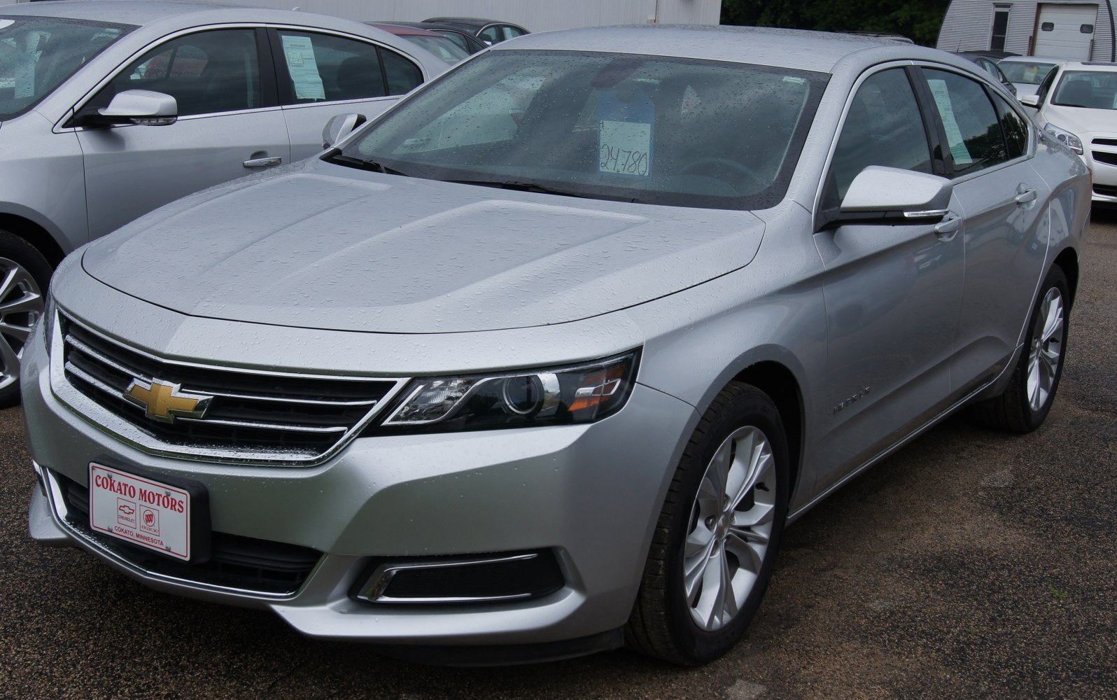 Front grille and headlights of silver sedan with rain droplets