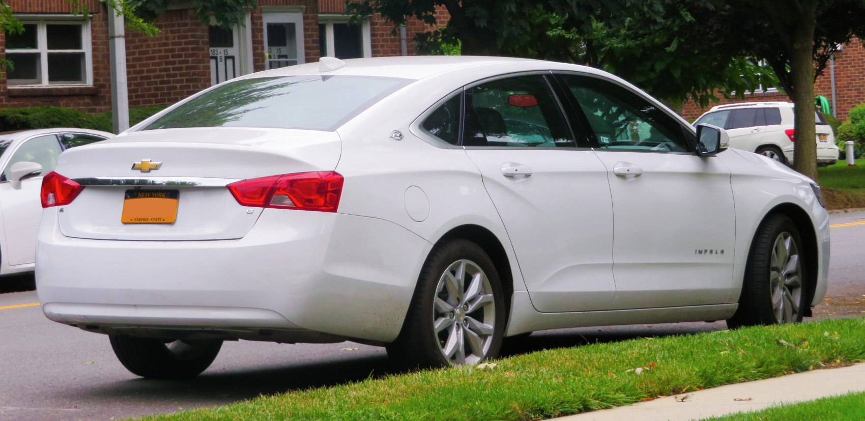 Rear and side profile of a white sedan with alloy wheels and distinct taillights
