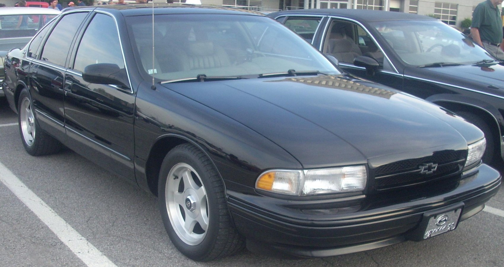 Front three-quarter view of black sedan with classic headlights and alloy wheels