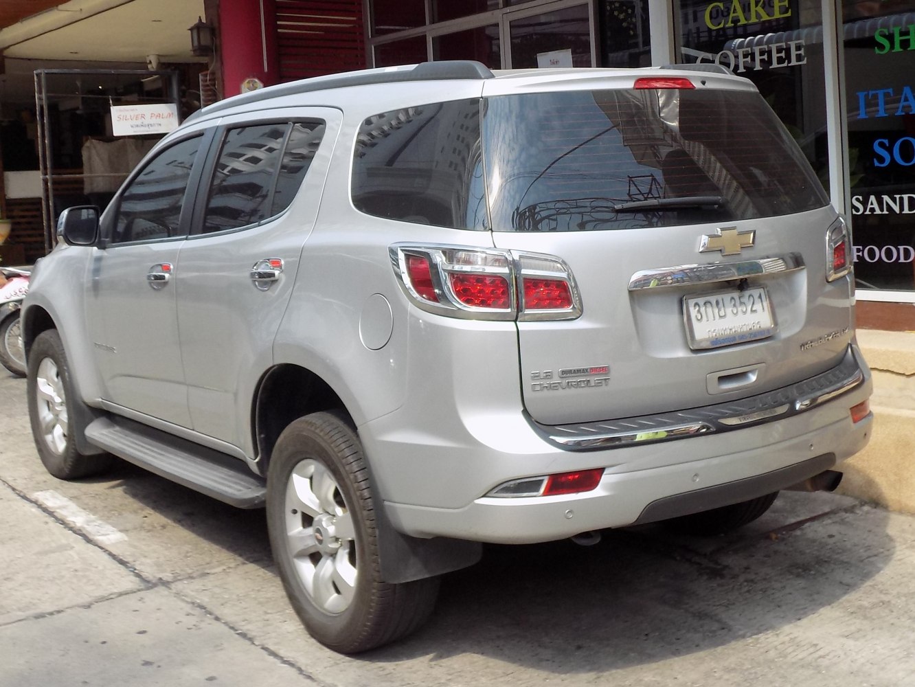 Rear and side view of silver SUV with distinctive tail lights and roof rails