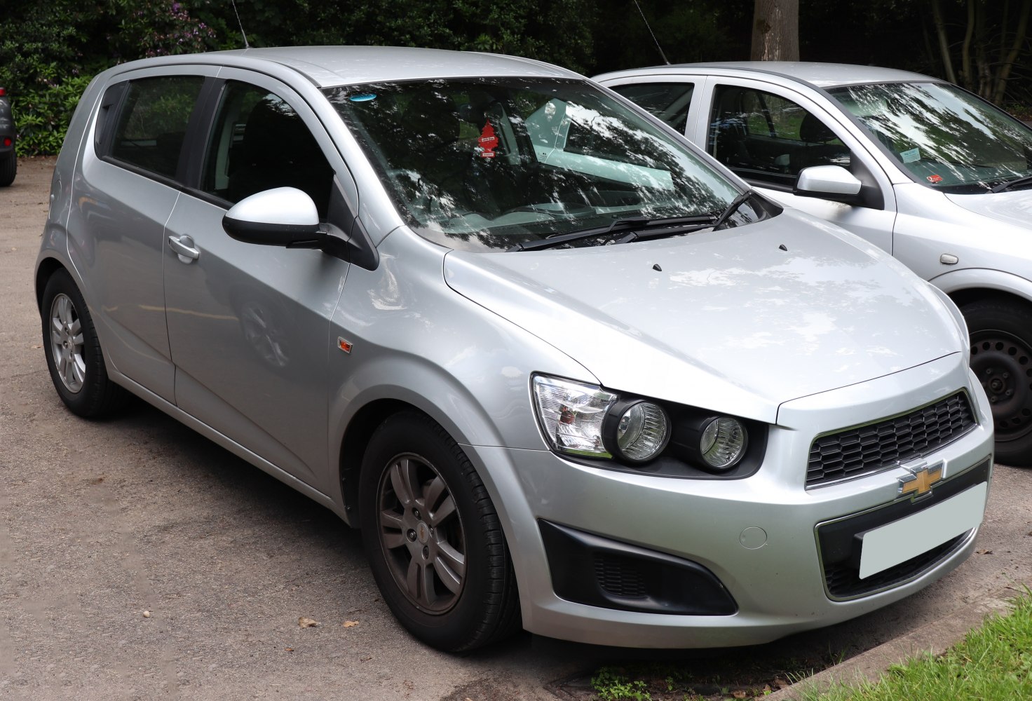 Silver compact hatchback with dual round headlights and black grille
