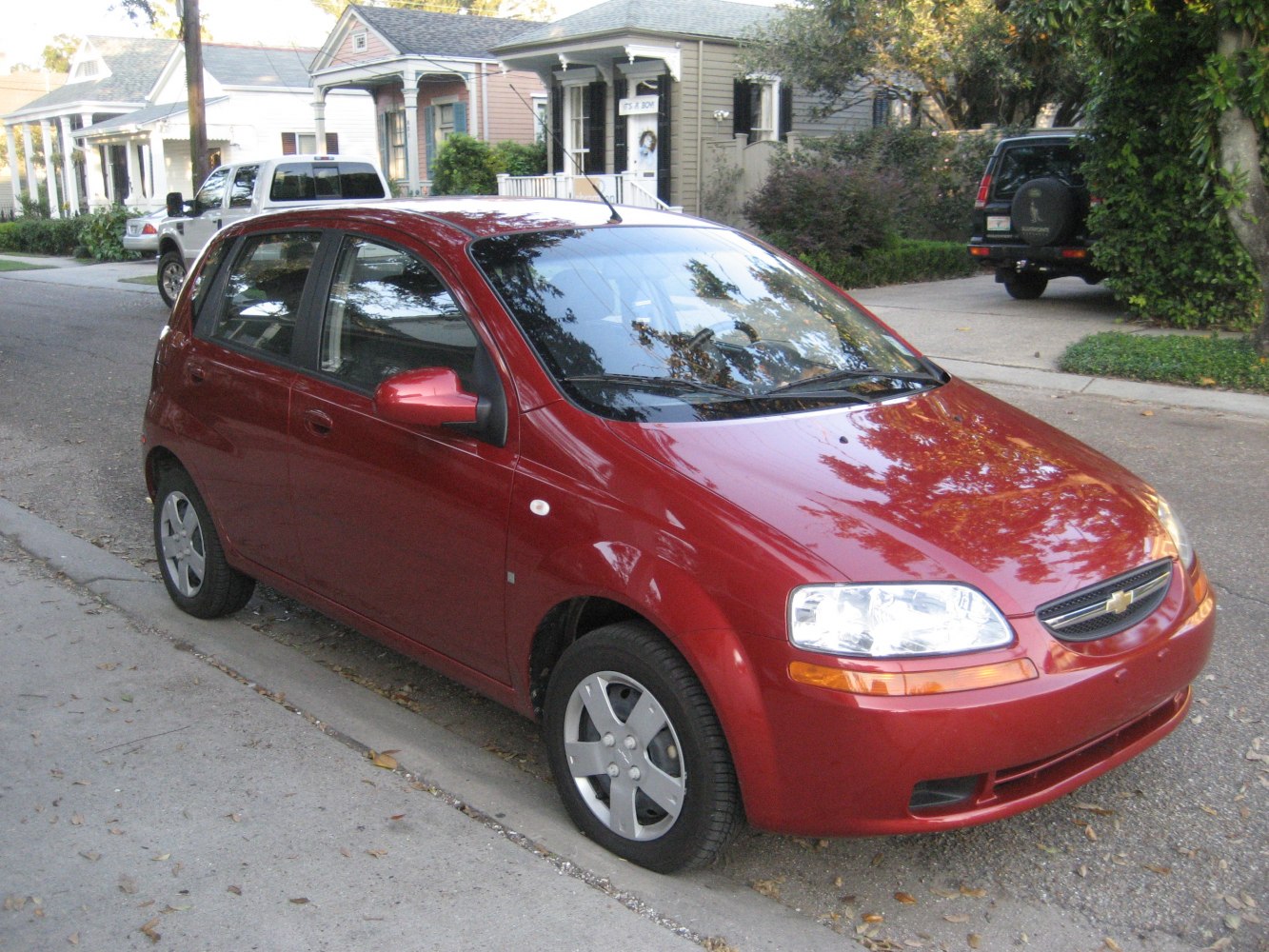 Front side view of a red hatchback with clear headlights and grille.