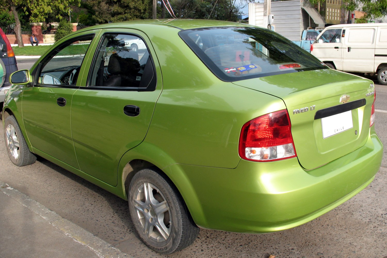 Rear side view of a green compact sedan with alloy wheels and taillights