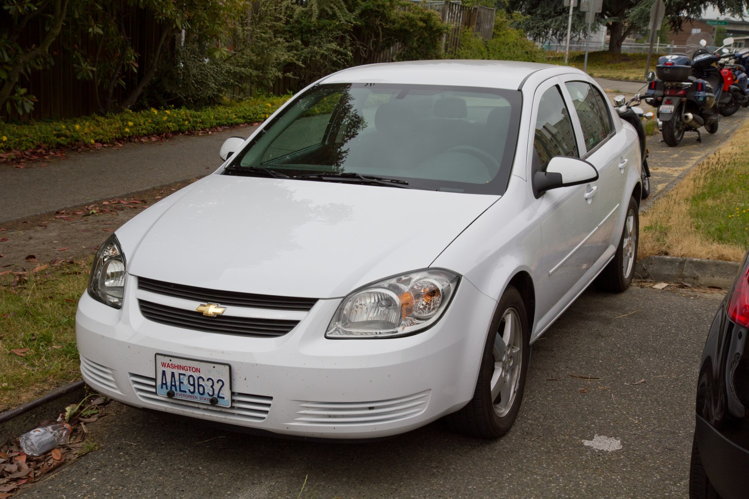White compact sedan front view with headlights and grille
