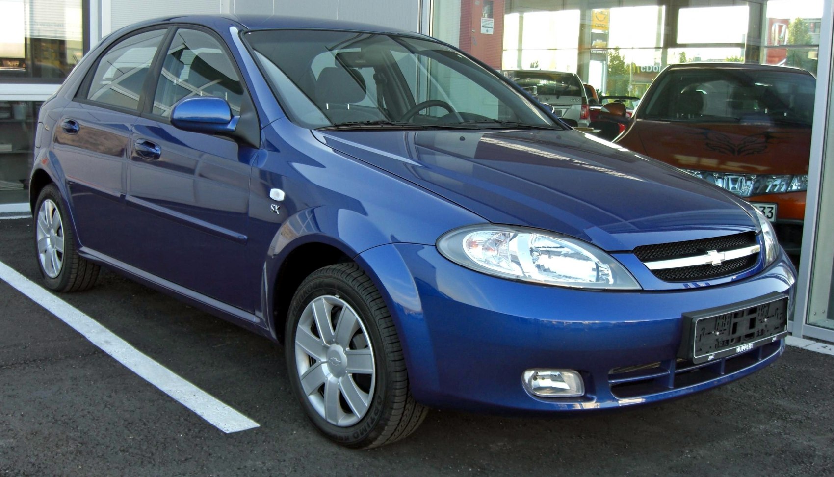 Front and side profile of a blue hatchback with alloy wheels and clear headlights